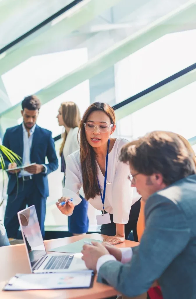 a woman is point out information to her colleague on a laptop computer