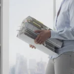 profile of person carrying multiple folders in an office setting